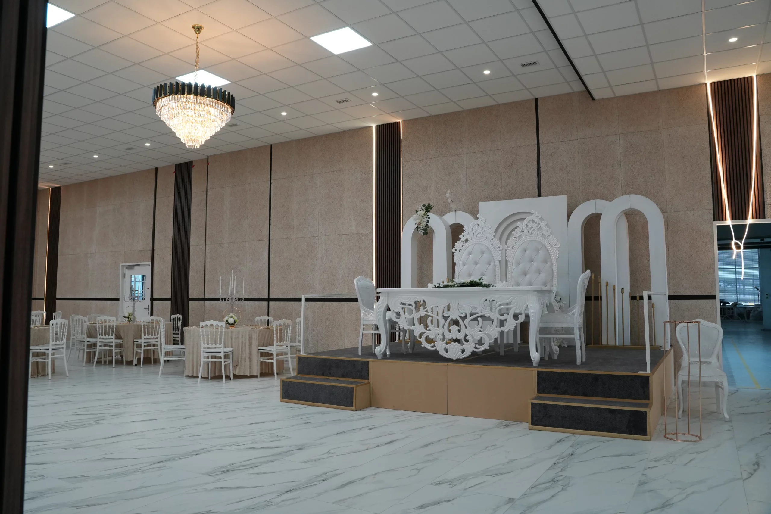 Wedding venue hall with raised bridal stage, ornate white sweetheart table, throne chairs and marble floor at AWA Zug Switzerland