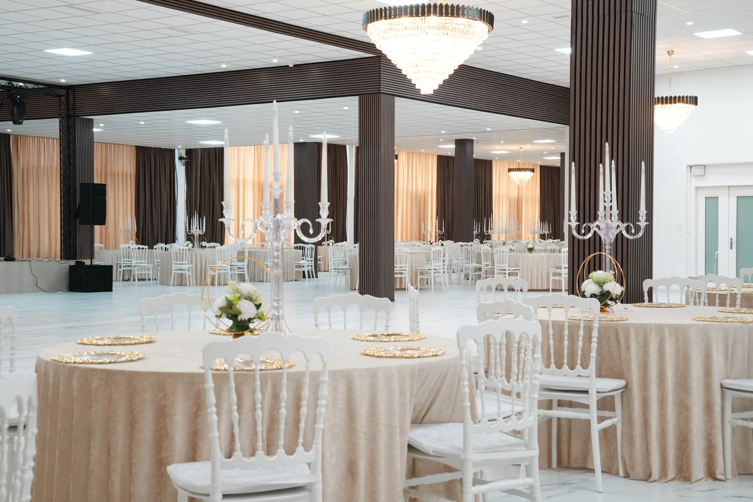 Grand ballroom with open dance floor, performance stage, crystal chandeliers and elegantly set tables at AWA Zug event venue