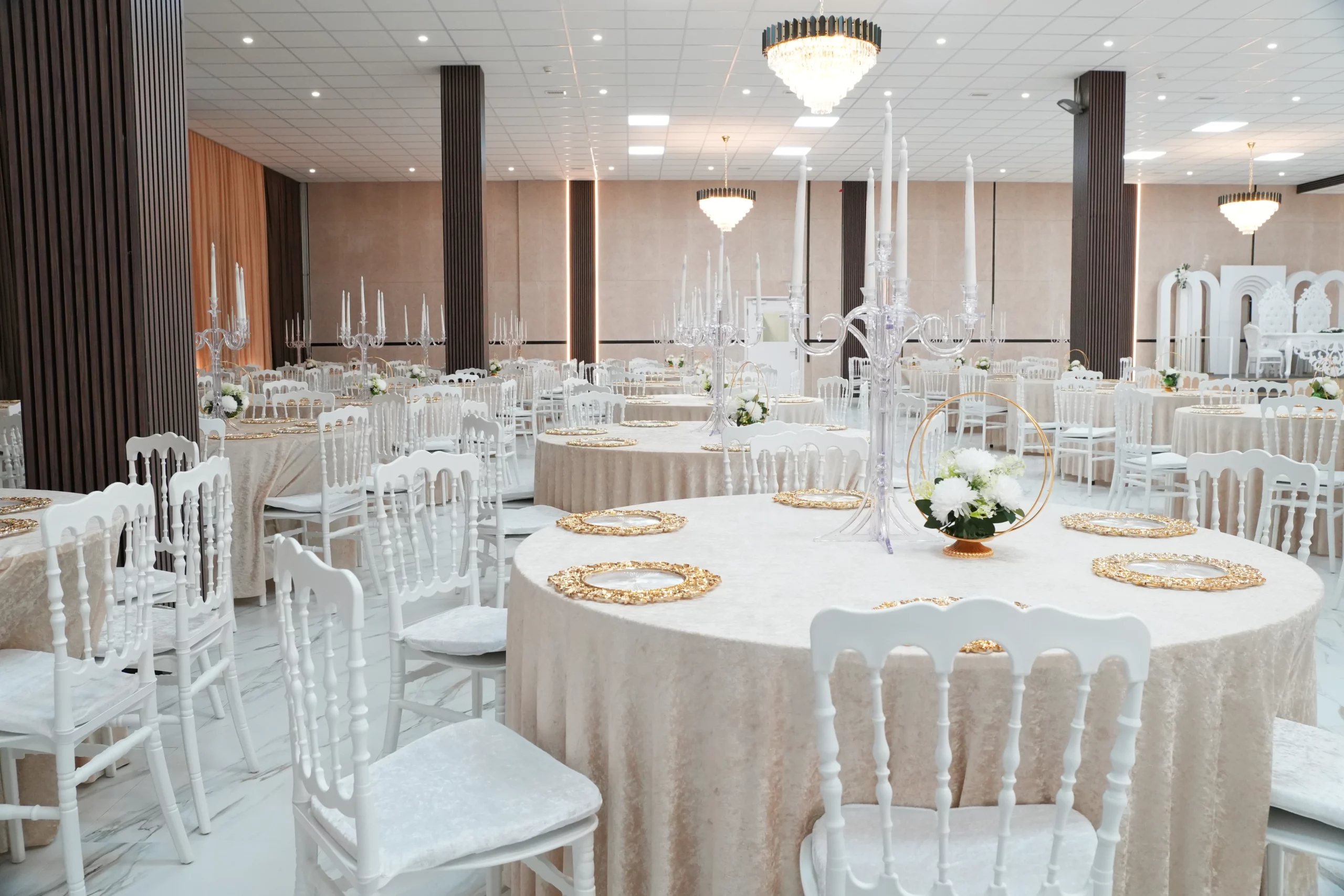 Wedding banquet hall with white Chiavari chairs, gold charger plates, crystal candelabras and chandelier lighting at AWA Zug