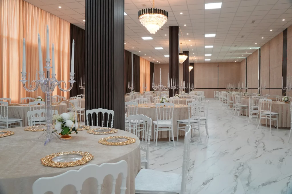 Elegant event hall with white Chiavari chairs, round tables, crystal chandeliers and marble floor at AWA Zug venue