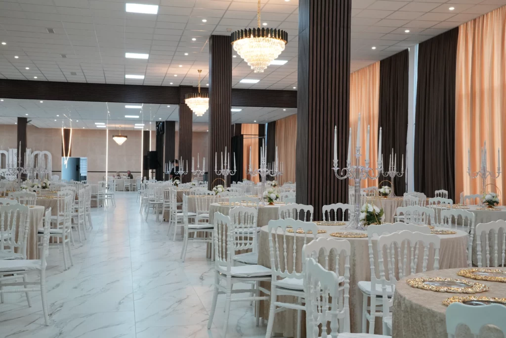 Large wedding hall with full table setup, crystal candelabras, beige drape wall and marble floor seating up to 900 guests at AWA Zug