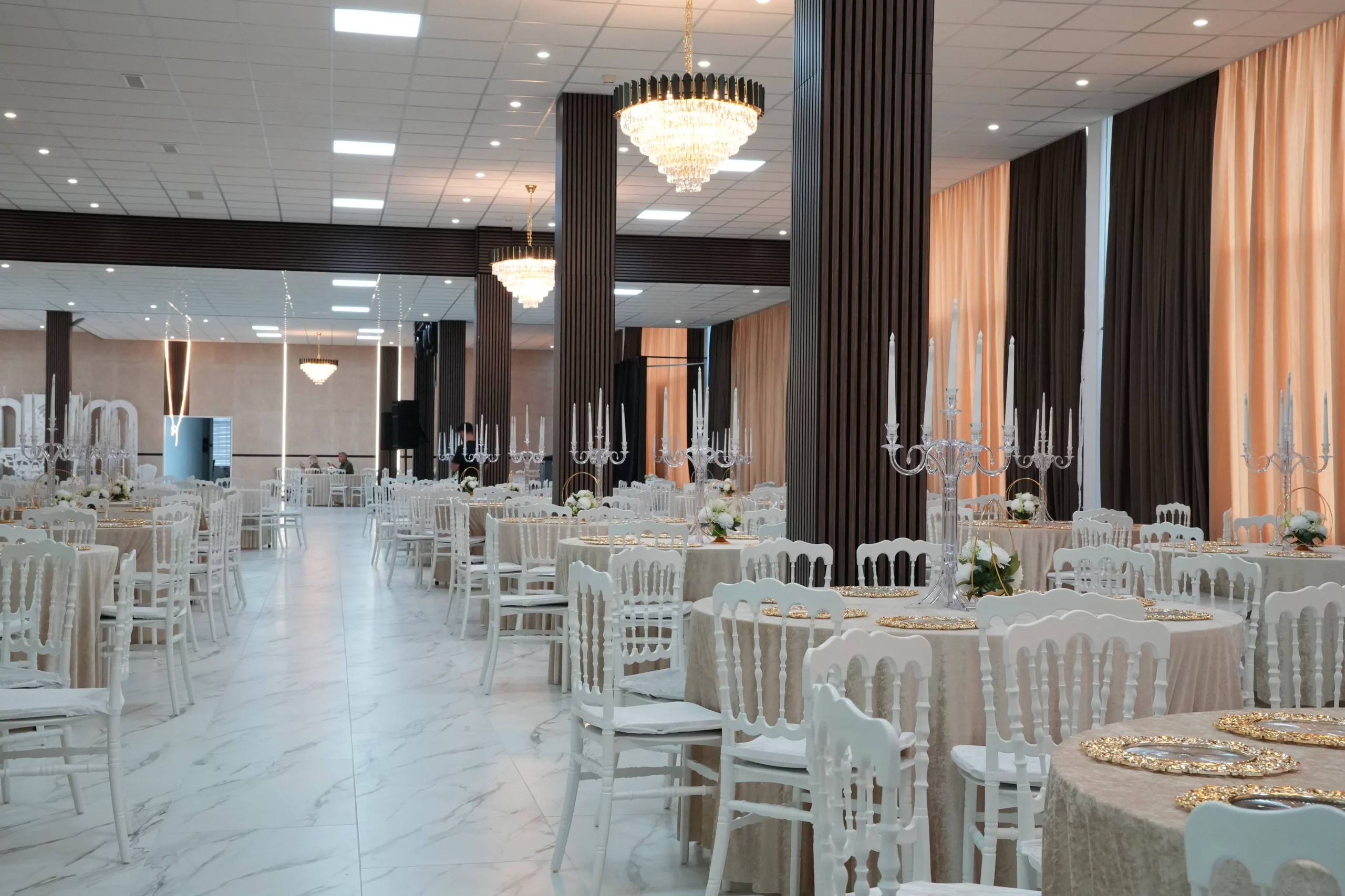 Large wedding hall with full table setup, crystal candelabras, beige drape wall and marble floor seating up to 900 guests at AWA Zug
