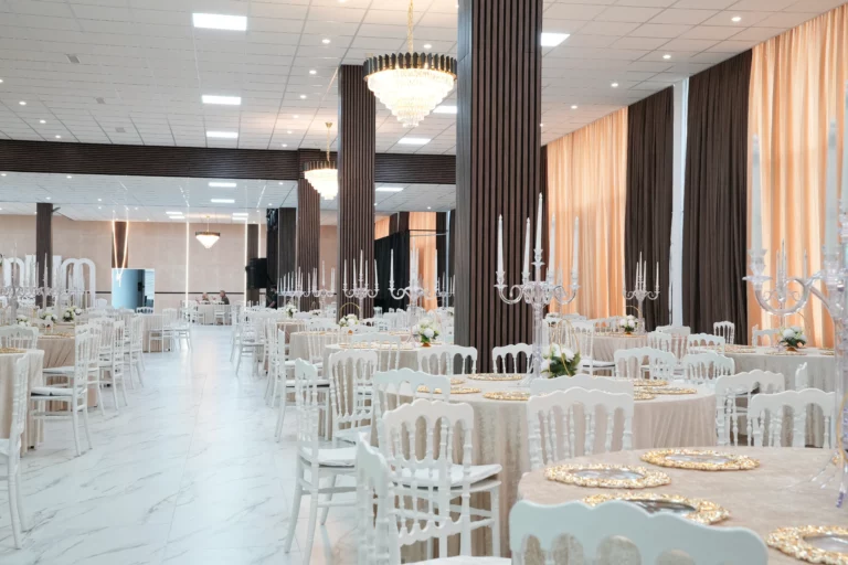 Large wedding hall with full table setup, crystal candelabras, beige drape wall and marble floor seating up to 800 guests at AWA Zug