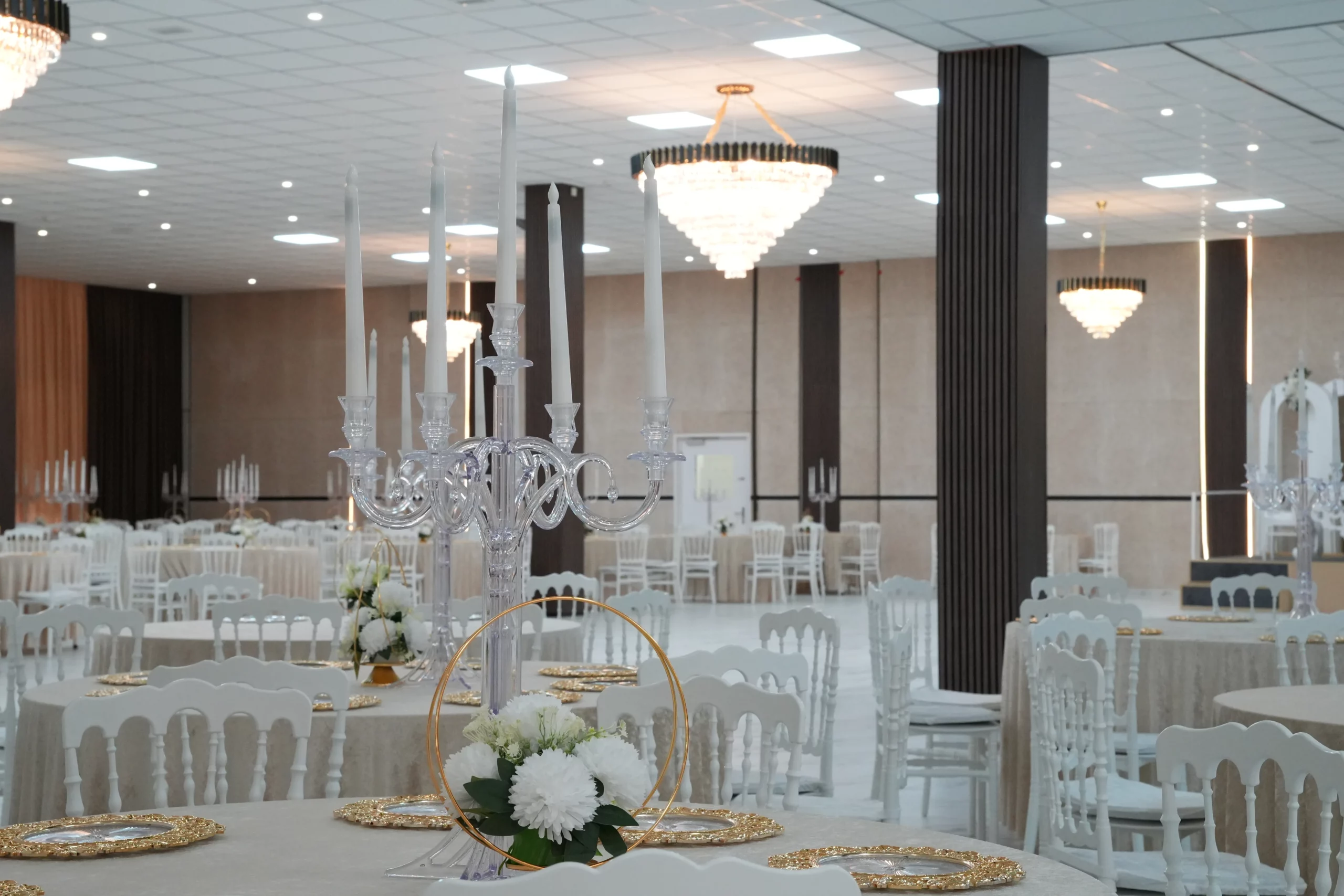 Fully decorated wedding banquet hall with multiple crystal chandeliers, candelabras and white floral centerpieces at AWA Zug event venue Switzerland