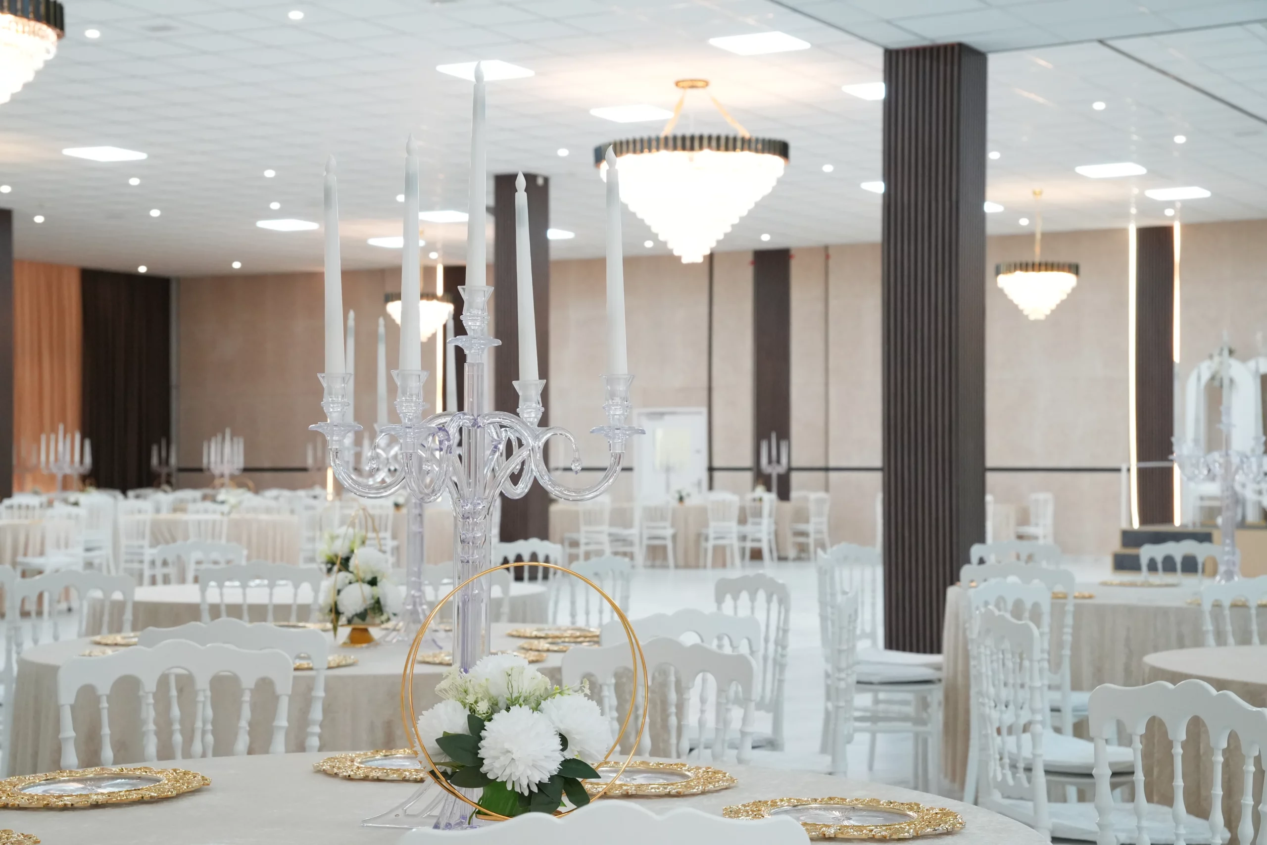 Fully decorated wedding banquet hall with multiple crystal chandeliers, candelabras and white floral centerpieces at AWA Zug event venue Switzerland
