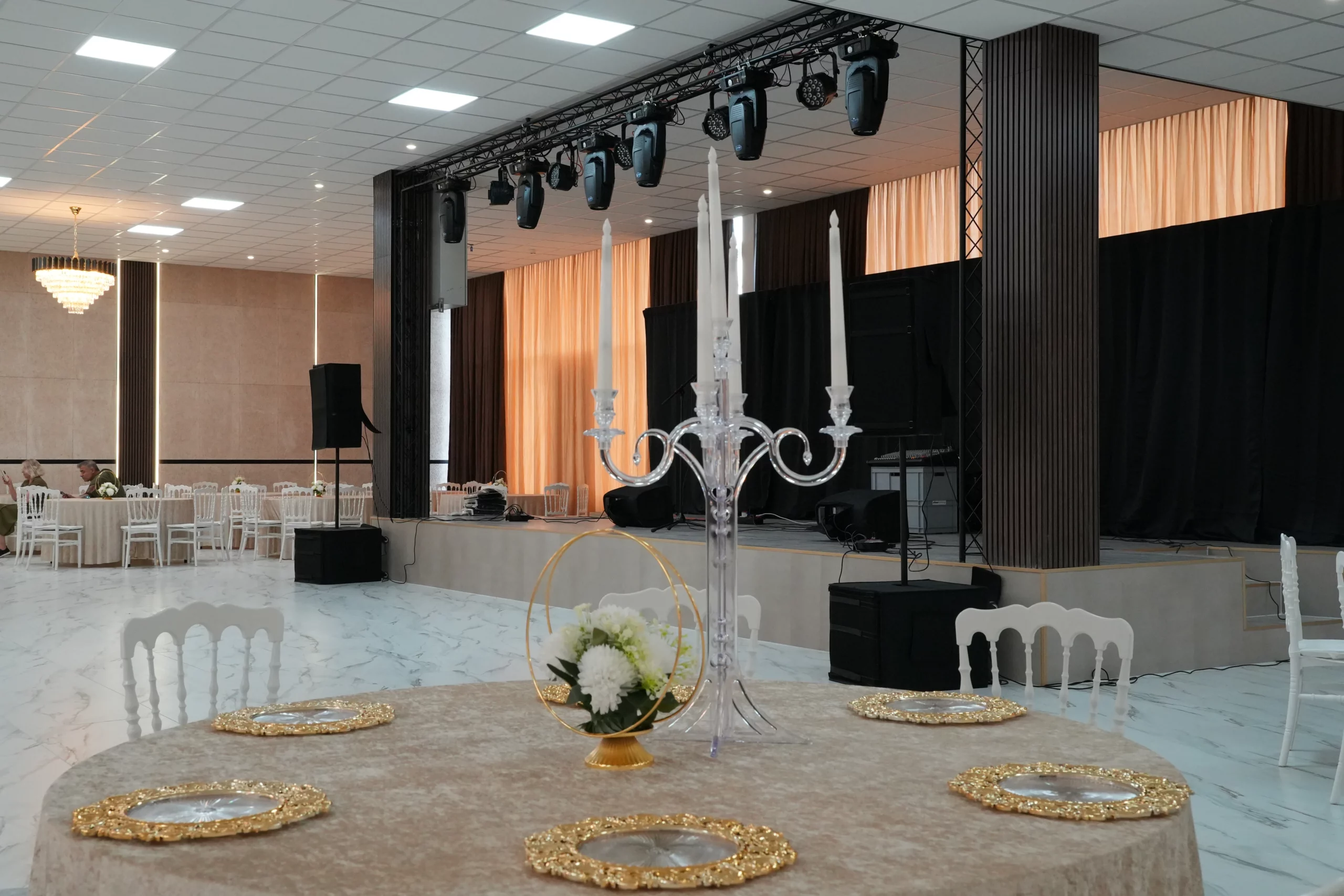 Wedding table centerpiece with crystal candelabra and gold hoop floral arrangement in front of event stage at AWA Zug venue